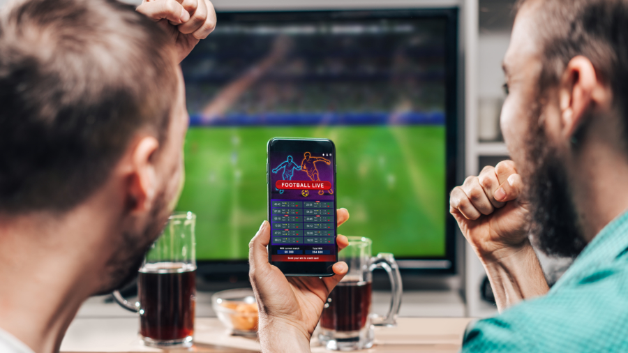 Two male friends watching live football game broadcast on tv